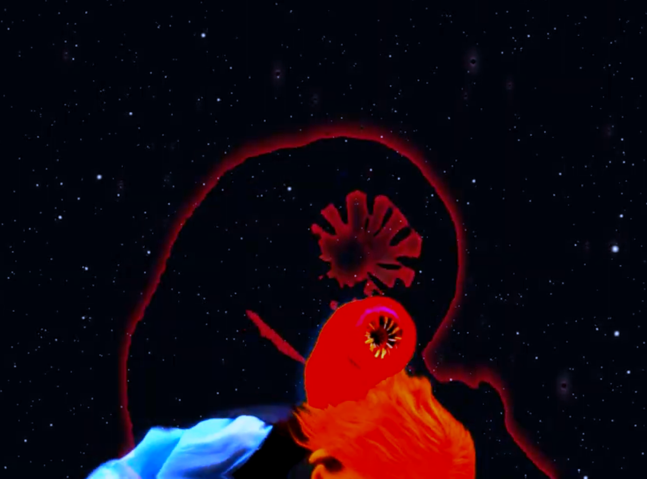 A puppet head has a galactic space worm or brain worm coming out of it.  The worm is a puppet the background is space.