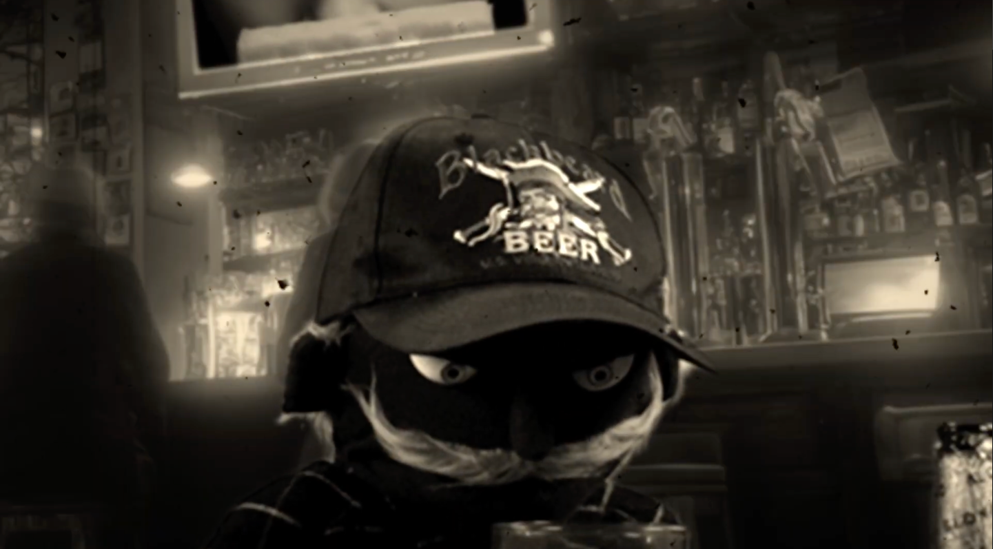 A puppet wearing a black hat is looking sad in a bar.